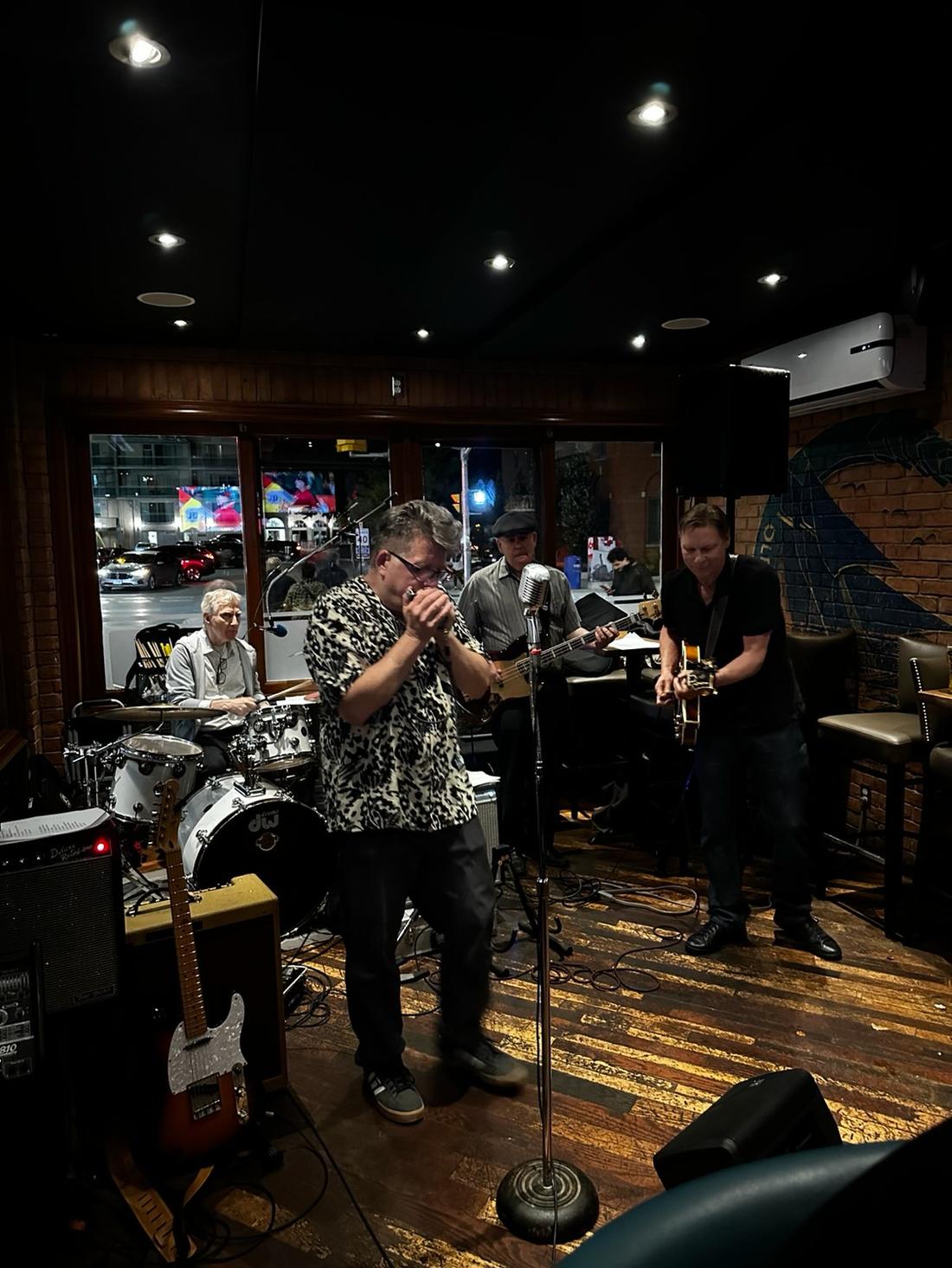 The full band playing inside the Pump House Grille Co. with the street visible through the window