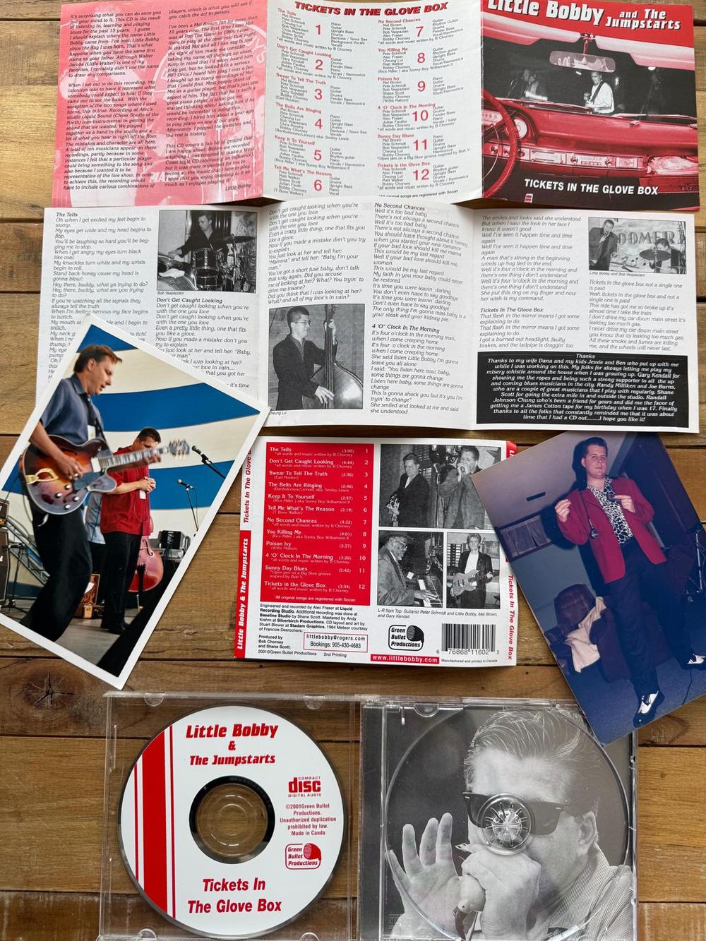 The Tickets in the Glove Box CD, booklet, lyric sheet and two old band photos laid out on a wooden table