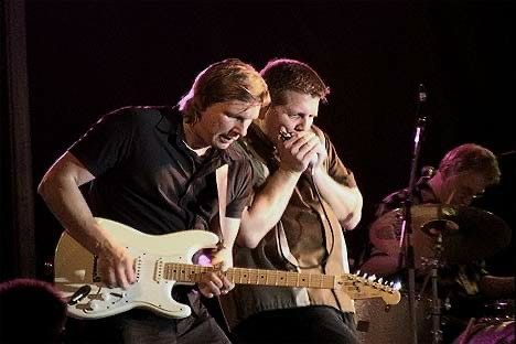 Little Bobby on harmonica leaning in next to the guitarist mid-solo